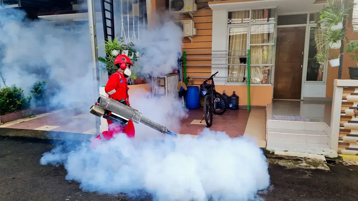 Pest control technician working along the exterior of a house